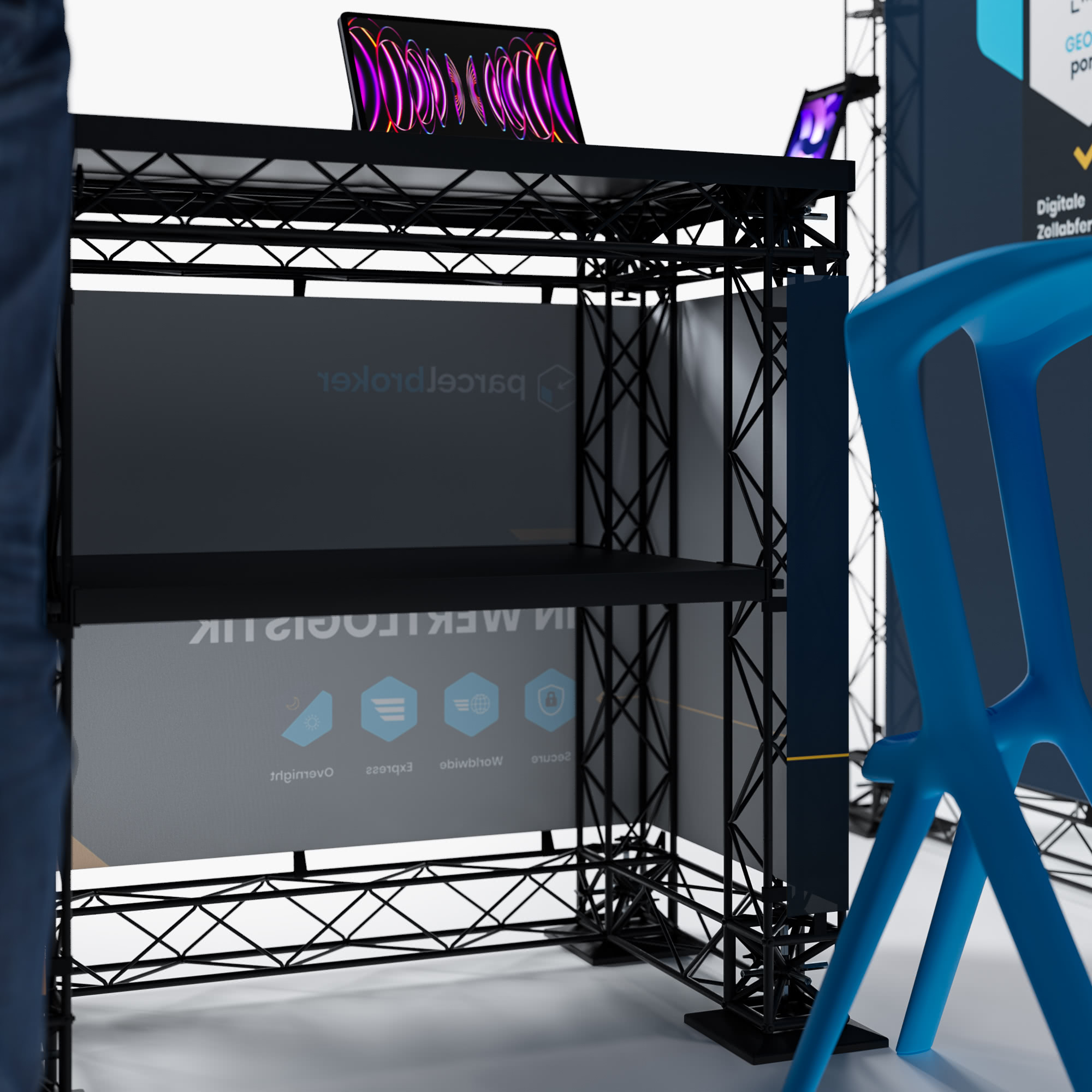 Ein schwarzer Metalltisch mit einem Laptop darauf und einem blauen Plastikstuhl daneben. Im Hintergrund ist ein teilweise sichtbares Banner zu sehen, und es scheint sich um eine Ausstellung oder Messe zu handeln.