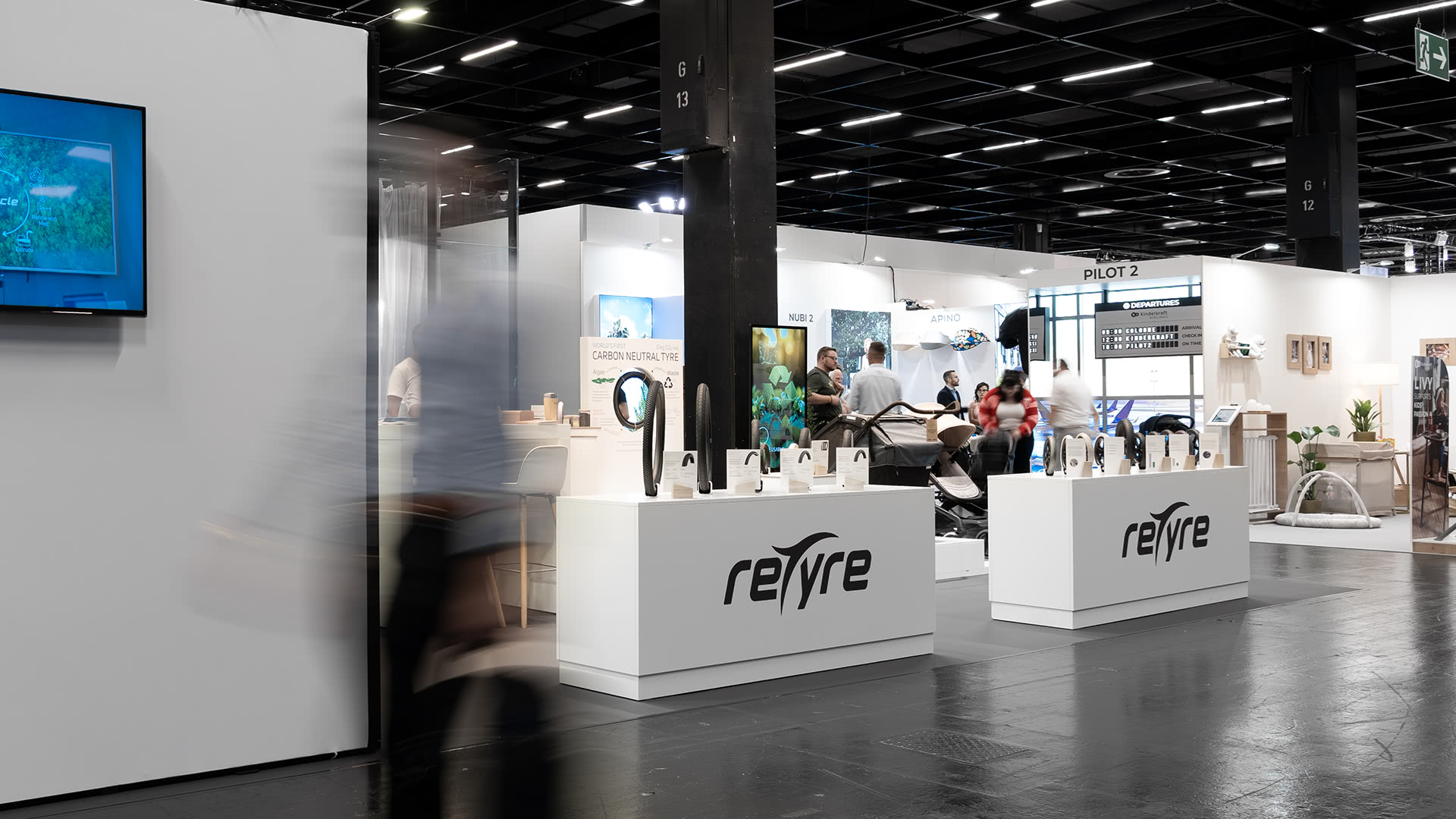 Ein moderner Messestand mit Retyre-Branding, Produktdisplays und interagierenden Menschen.