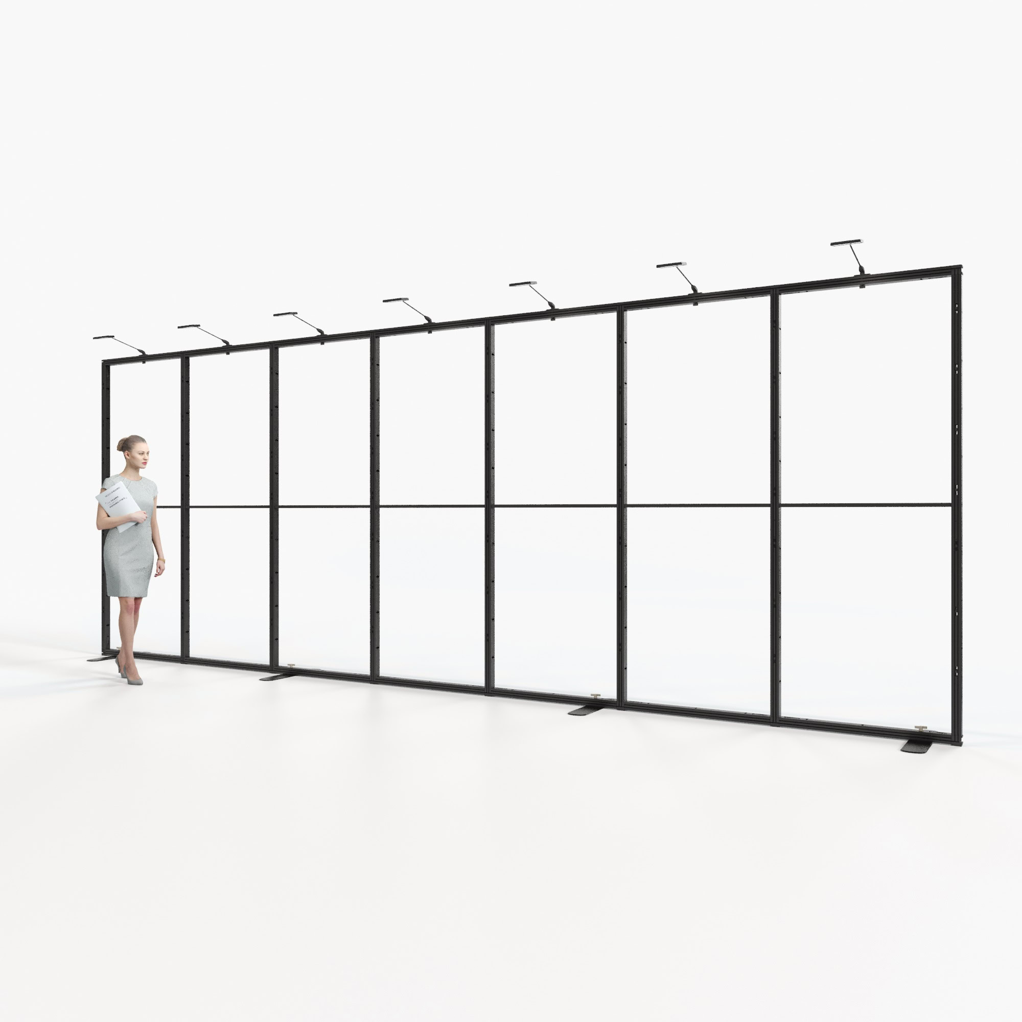 Eine Frau in Berufskleidung steht in einem modernen, geräumigen und hellen Büro mit großen Fenstern und Industriebeleuchtung und blickt auf eine lange, schwarze Metallrahmenkonstruktion. Durch die Fenster sind städtische Gebäude zu sehen.